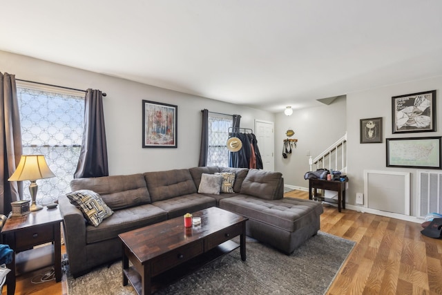 living room with stairway, wood finished floors, and visible vents
