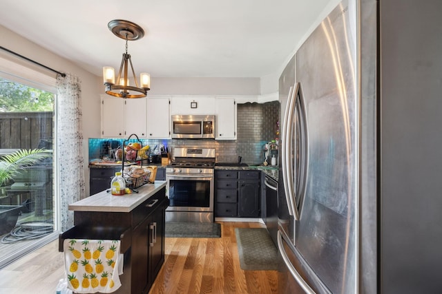 kitchen with decorative backsplash, light wood-type flooring, a chandelier, white cabinets, and stainless steel appliances