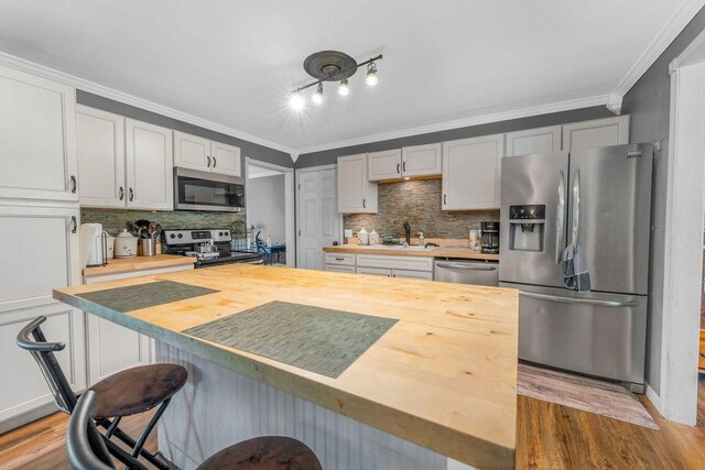 418 Mason Ln, Goodlettsville, TN 37072 - kitchen with appliances with stainless steel finishes, wood counters, light wood finished floors, backsplash, and crown molding