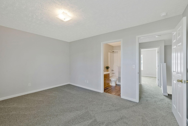 unfurnished bedroom with baseboards, carpet, ensuite bath, and a textured ceiling