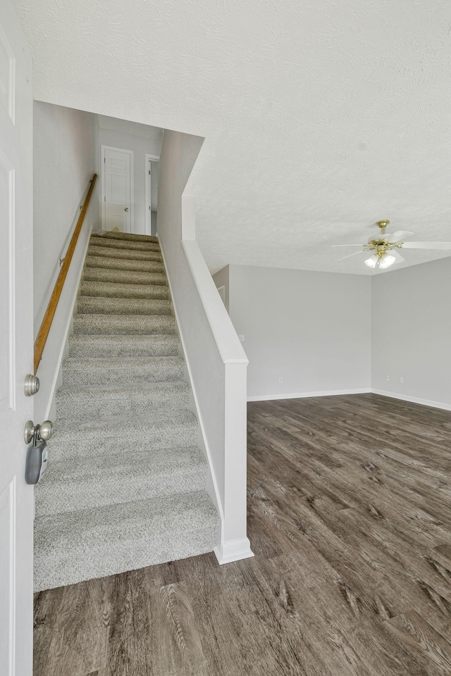 stairs with baseboards, a textured ceiling, ceiling fan, and wood finished floors