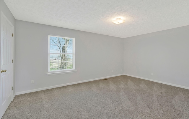 empty room featuring baseboards, carpet, and a textured ceiling