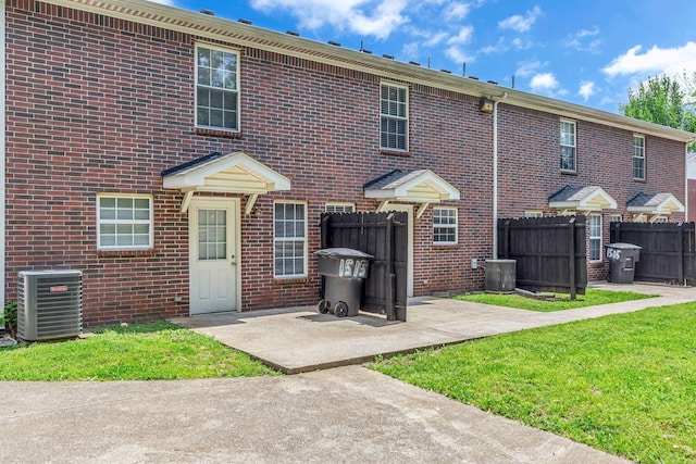 back of property with brick siding, central AC, and fence