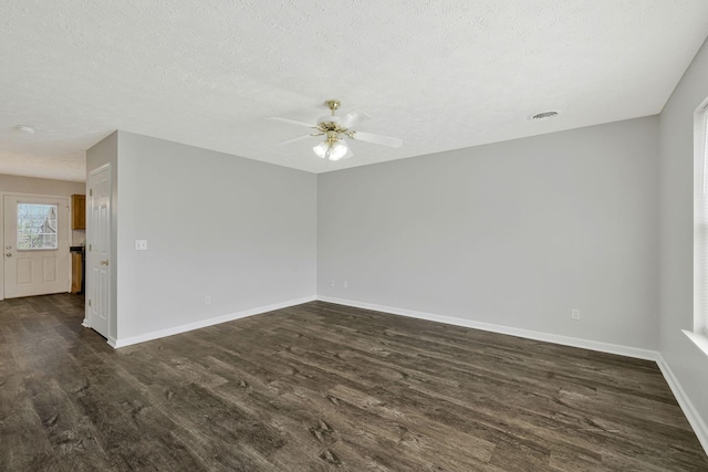 unfurnished room with a textured ceiling, dark wood finished floors, a ceiling fan, baseboards, and visible vents