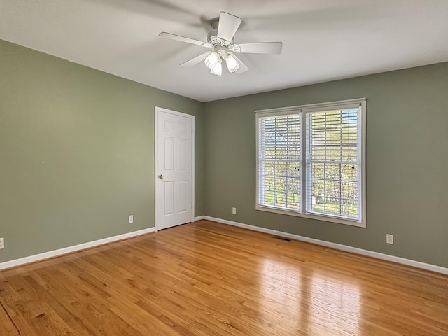 spare room featuring baseboards, a ceiling fan, visible vents, and light wood-type flooring