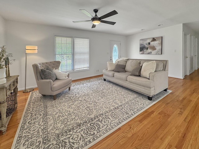 living area with a ceiling fan, baseboards, and light wood-style floors