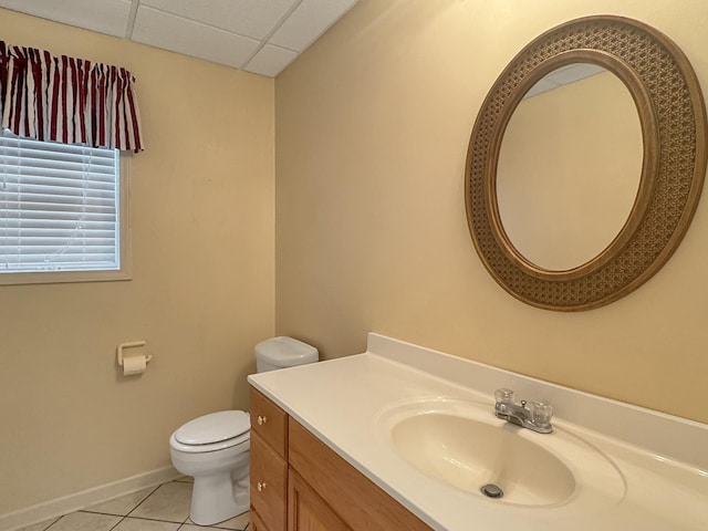 bathroom featuring vanity, tile patterned floors, baseboards, toilet, and a drop ceiling