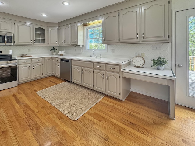 kitchen featuring light wood-type flooring, a sink, backsplash, and stainless steel appliances