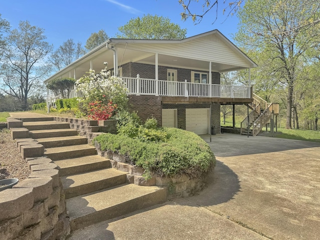 view of side of home with stairway, brick siding, concrete driveway, and a garage