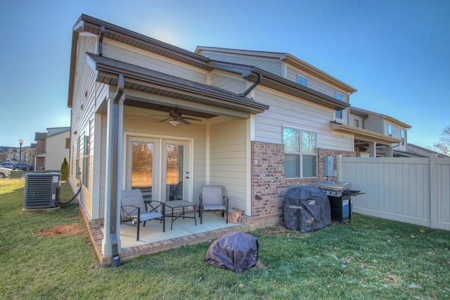 rear view of property featuring a ceiling fan, a yard, cooling unit, and a patio area