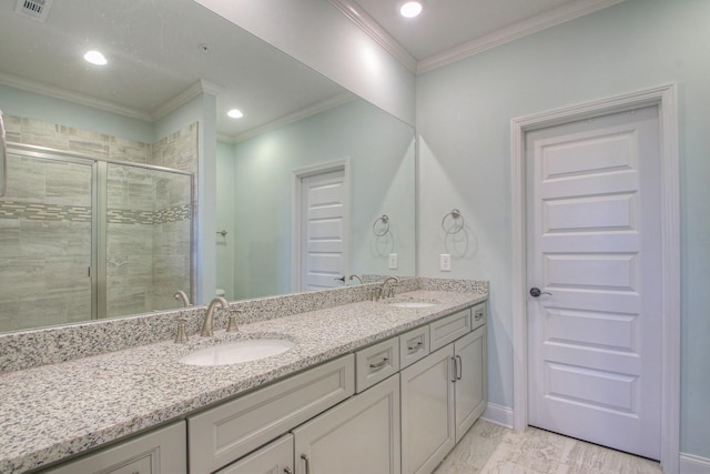bathroom featuring crown molding, double vanity, a shower stall, and a sink