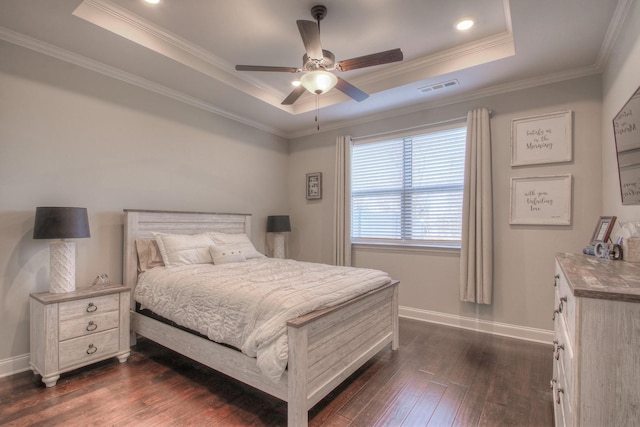 bedroom featuring dark wood-type flooring, a raised ceiling, crown molding, and baseboards
