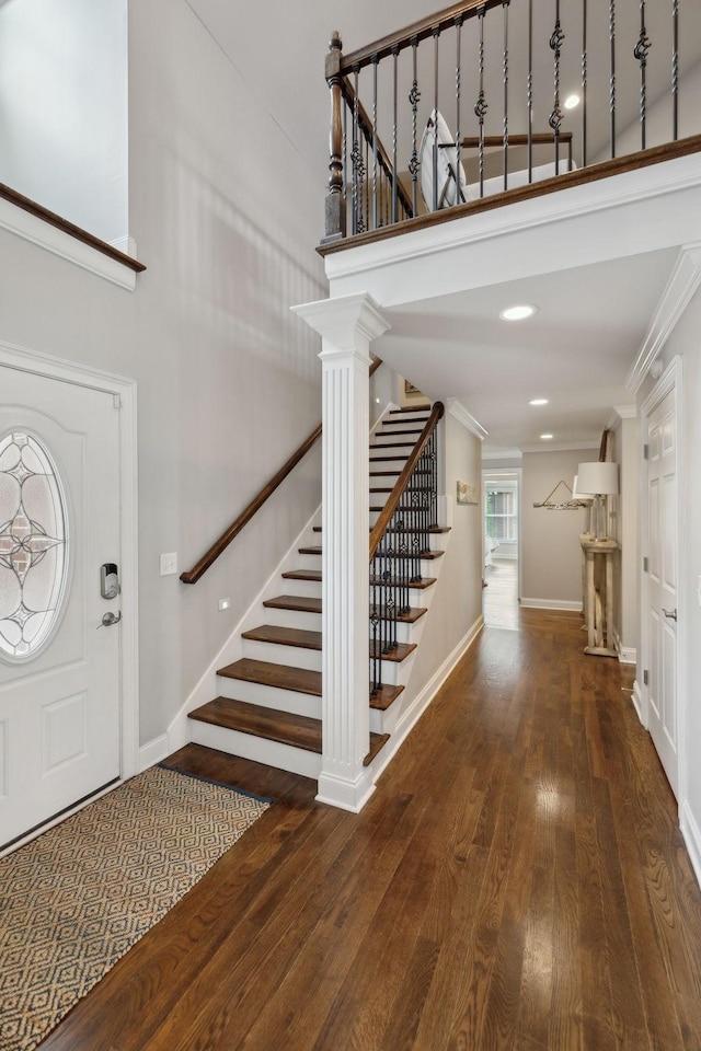 foyer featuring crown molding, a high ceiling, stairs, baseboards, and hardwood / wood-style flooring