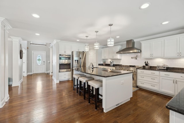kitchen featuring appliances with stainless steel finishes, decorative backsplash, wall chimney exhaust hood, and white cabinets