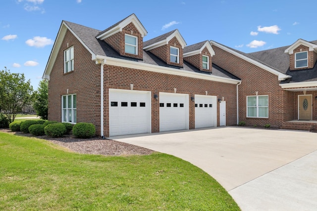 view of front facade featuring an attached garage, concrete driveway, a front yard, and brick siding