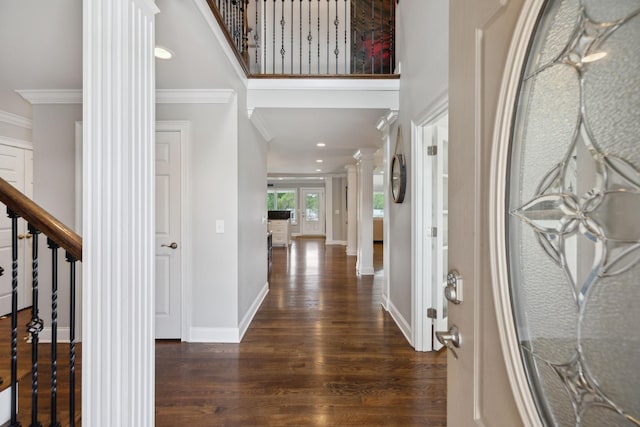 entryway featuring decorative columns, crown molding, wood finished floors, baseboards, and stairs