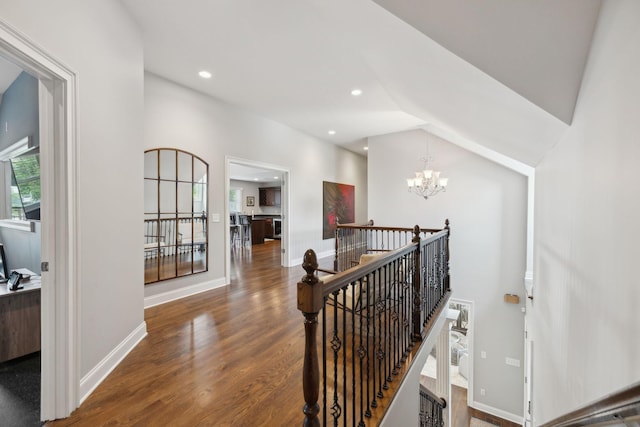 hallway with baseboards, an upstairs landing, an inviting chandelier, and wood finished floors