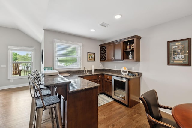 bar featuring beverage cooler, light wood finished floors, visible vents, and a healthy amount of sunlight