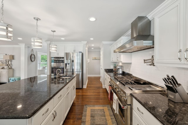 kitchen featuring backsplash, white cabinets, ornamental molding, stainless steel appliances, and wall chimney exhaust hood