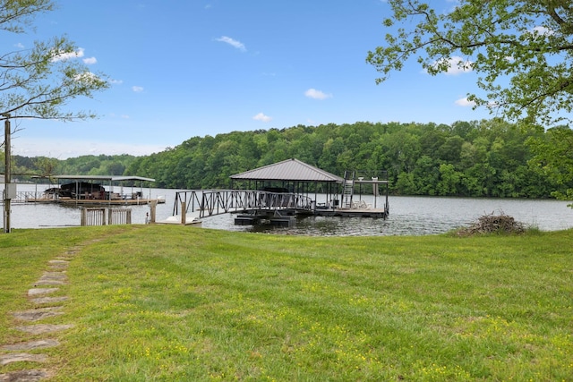 dock area with a lawn, a water view, and a wooded view