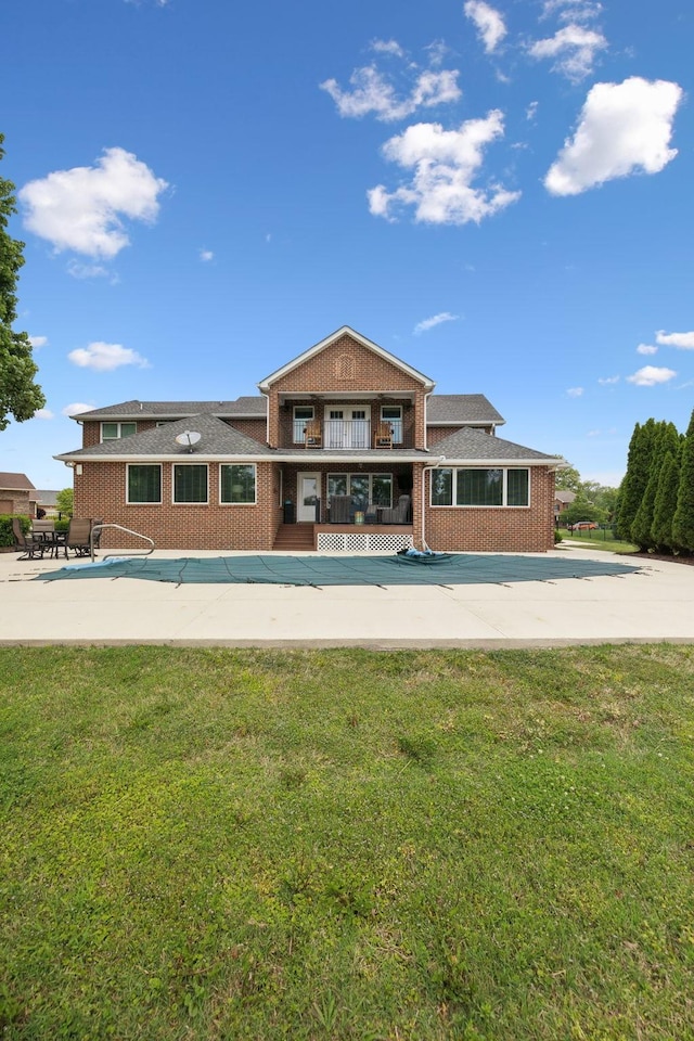 rear view of house with a lawn, a patio area, and brick siding