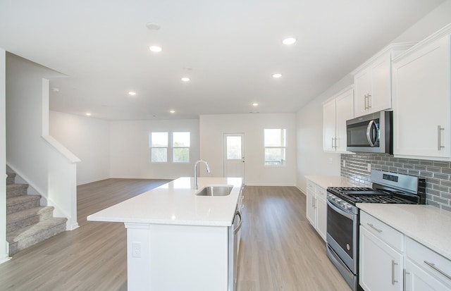 kitchen with a sink, light wood-style flooring, appliances with stainless steel finishes, and open floor plan