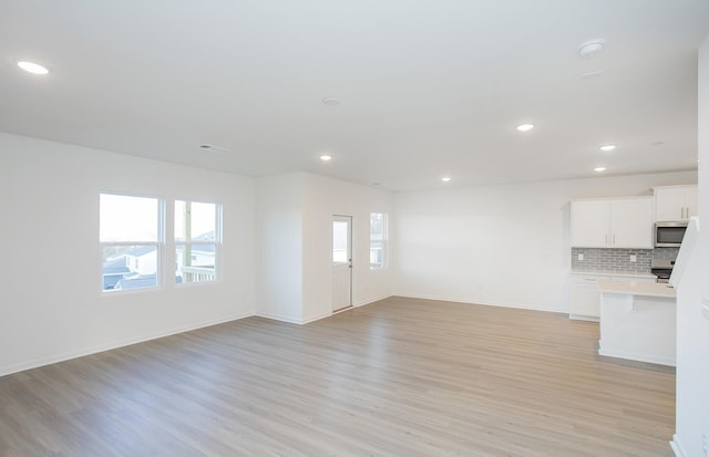 unfurnished living room with recessed lighting, baseboards, and light wood-style flooring