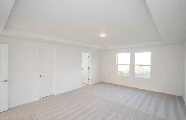 unfurnished room with baseboards, light carpet, and a tray ceiling