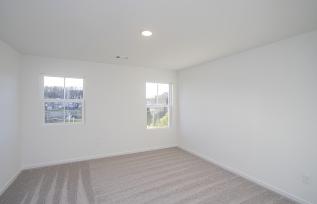 empty room with carpet flooring, recessed lighting, baseboards, and visible vents