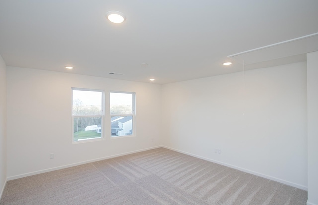 unfurnished room featuring recessed lighting, attic access, baseboards, and light colored carpet