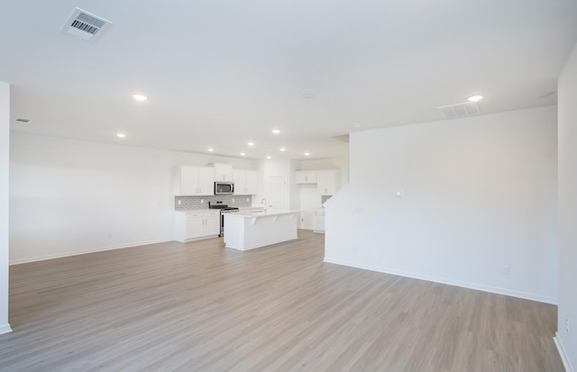 unfurnished living room featuring visible vents, recessed lighting, light wood-style floors, and baseboards