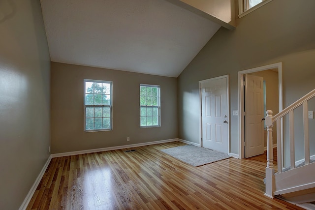 unfurnished room with light wood-type flooring, stairs, baseboards, and high vaulted ceiling