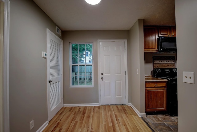 interior space featuring baseboards, black appliances, and light wood-type flooring