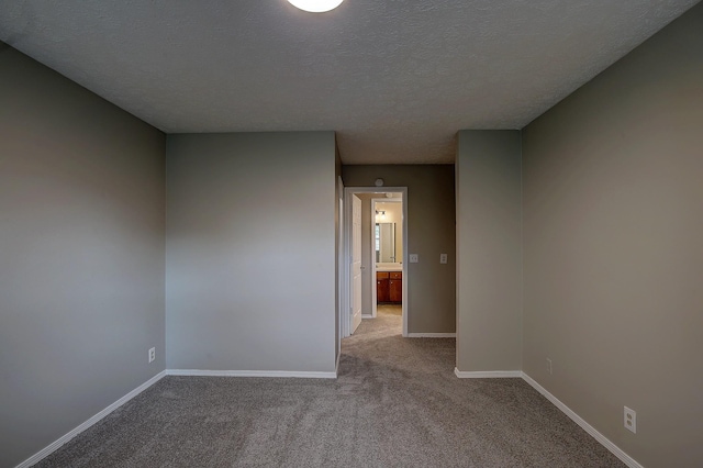 unfurnished room featuring a textured ceiling, light colored carpet, and baseboards