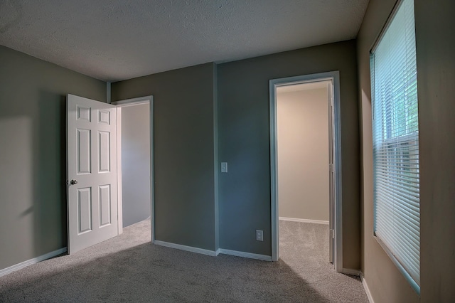 unfurnished bedroom featuring a textured ceiling, baseboards, and carpet