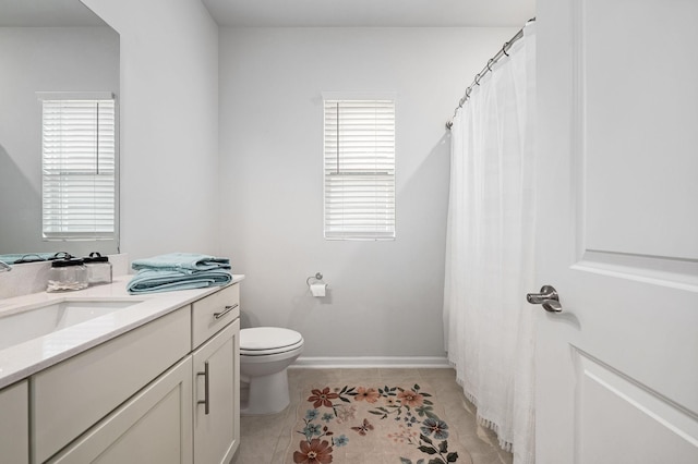 full bath featuring vanity, baseboards, tile patterned flooring, and toilet