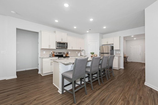 kitchen with an island with sink, white cabinetry, appliances with stainless steel finishes, and tasteful backsplash