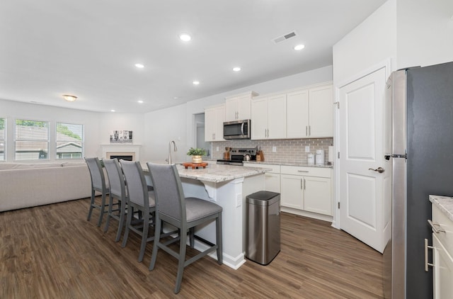 kitchen featuring stainless steel appliances, open floor plan, visible vents, and dark wood-type flooring