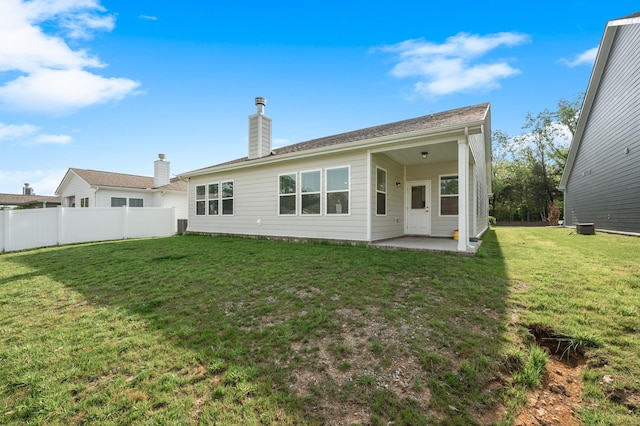 rear view of house featuring a patio area, fence, a yard, and a chimney