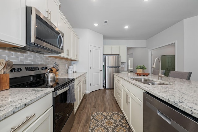kitchen featuring light stone countertops, white cabinets, a sink, backsplash, and stainless steel appliances
