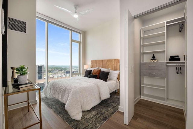 bedroom with floor to ceiling windows, multiple windows, wood finished floors, and visible vents
