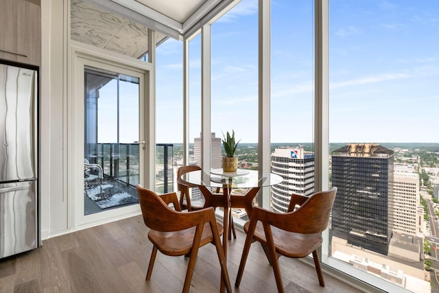 sunroom with a view of city, a wealth of natural light, expansive windows, and wood finished floors