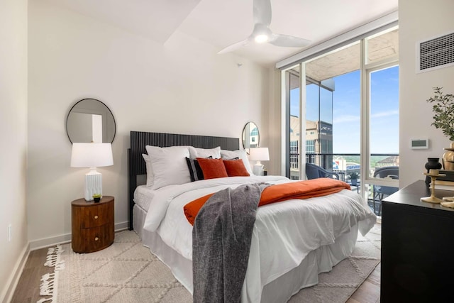 bedroom with a ceiling fan, wood finished floors, baseboards, a water view, and access to outside