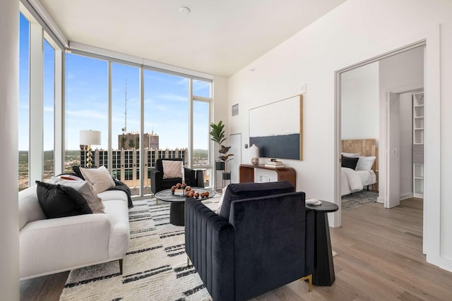 living room with a wall of windows, visible vents, wood finished floors, and a wealth of natural light