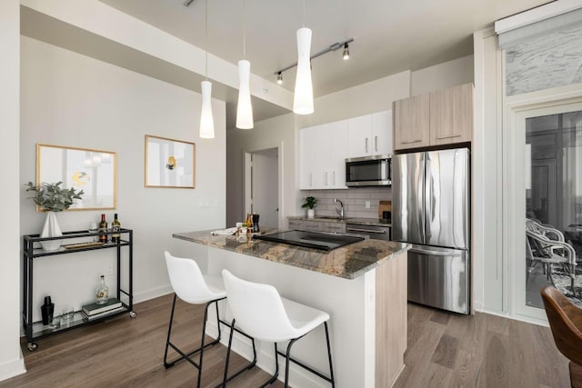 kitchen featuring a kitchen island, dark wood-style flooring, backsplash, appliances with stainless steel finishes, and a breakfast bar