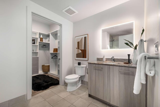 bathroom with visible vents, walk in shower, vanity, tile patterned floors, and toilet