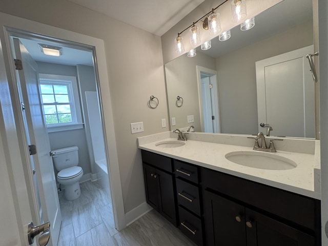 full bath with a sink, baseboards, toilet, and double vanity