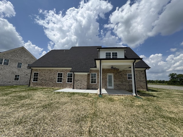 rear view of house featuring a yard, brick siding, a shingled roof, and a patio area