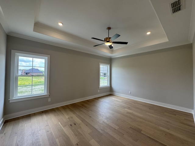 unfurnished room with visible vents, ornamental molding, wood finished floors, and a raised ceiling