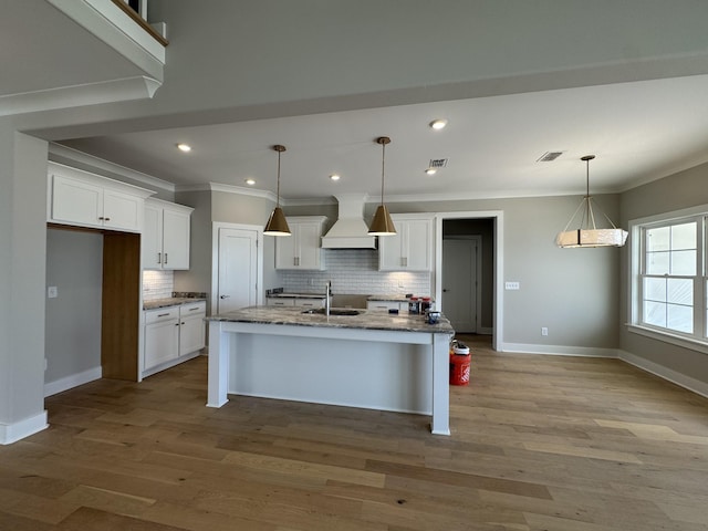 kitchen featuring a sink, premium range hood, crown molding, and decorative backsplash